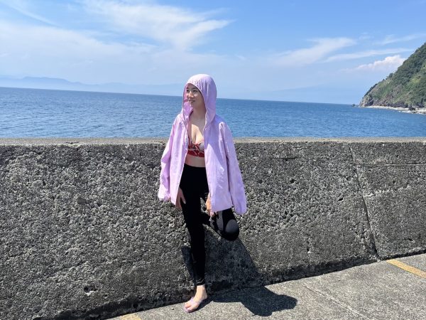 海の前でラッシュガードを着て写る女性