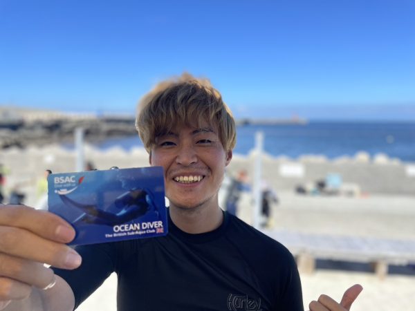 ダイビング男子がライセンスカードを手に持って写真を撮っている様子