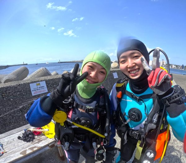 陸上でダイビング器材を背負った女性ダイバー2名
